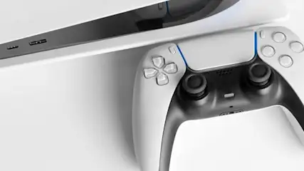 Na białym tle leży biało-czarny kontroler do gier wideo obok białej konsoli do gier wideo.