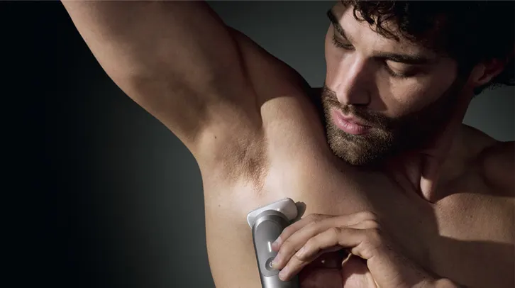 Mężczyzna golący ciało golarką Braun