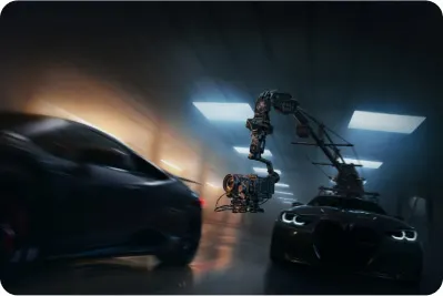 Dwa samochody sportowe w ciemnym tunelu, oświetlone światłami. Ramię kamery w tle filmuje pojazdy.