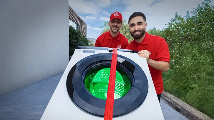 Dwóch mężczyzn w czerwonych koszulkach realizujący dostawę pralki