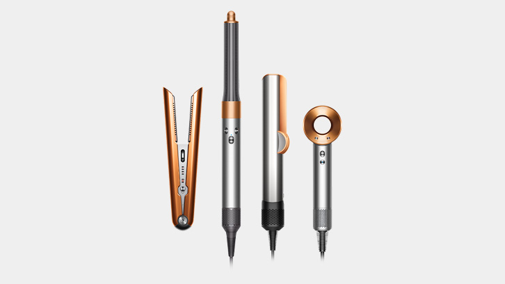 Na jasnym tle, cztery srebrne i miedziane urządzenia do stylizacji włosów, ustawione pionowo obok siebie.