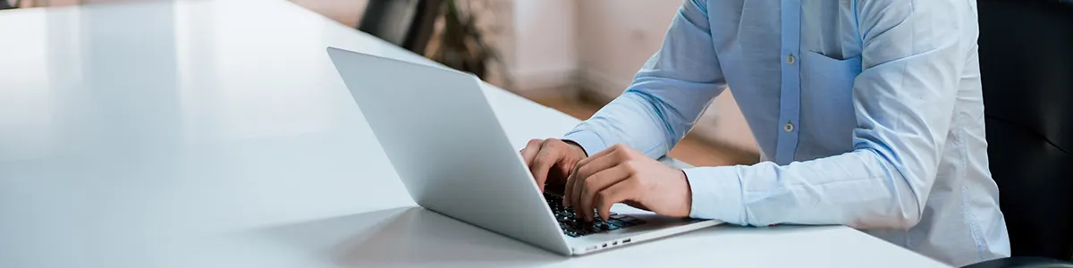 Osoba w niebieskiej koszuli pracuje na laptopie