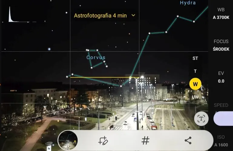 Nocny widok miasta z nałożonymi konstelacjami Hydra i Corvus oraz ustawieniami aparatu. Widoczne budynki, ulice i światła miejskie.