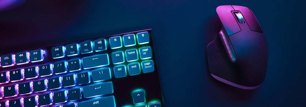 Klawiatura z podświetlanymi klawiszami obok szarej myszy na niebieskim tle.