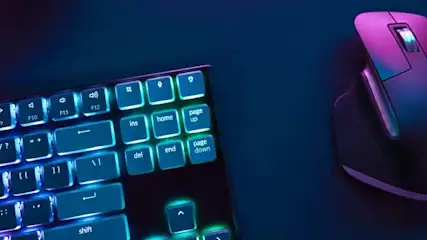 Klawiatura z podświetlanymi klawiszami obok szarej myszy na niebieskim tle.