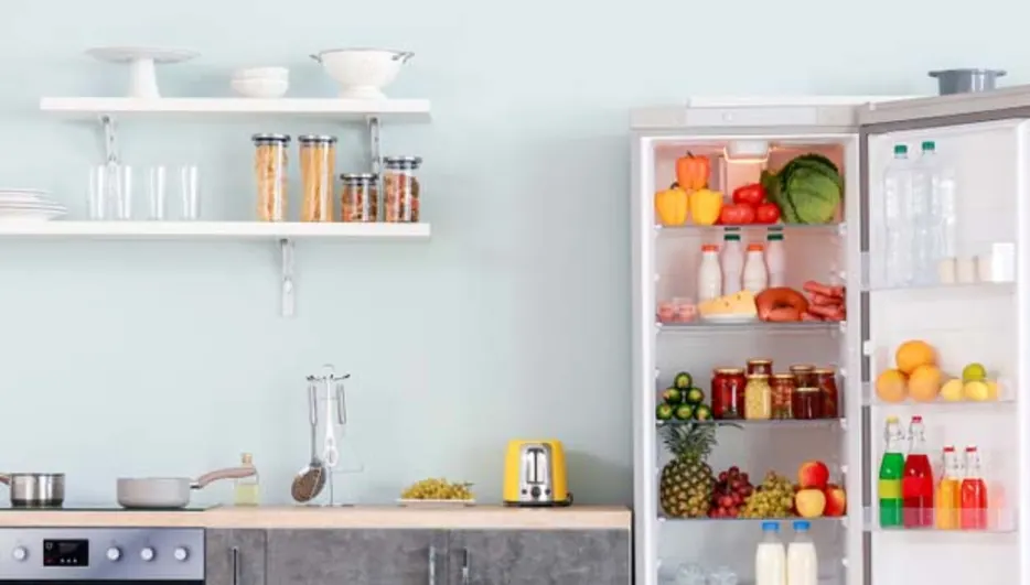 Kuchnia z otwartą lodówką, półkami i sprzętem AGD. Widoczne owoce, warzywa i naczynia.