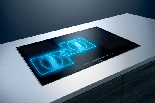 Czarna płyta indukcyjna na blacie, z niebieskimi ikonami termometru i strzałki wskazującej kierunek.