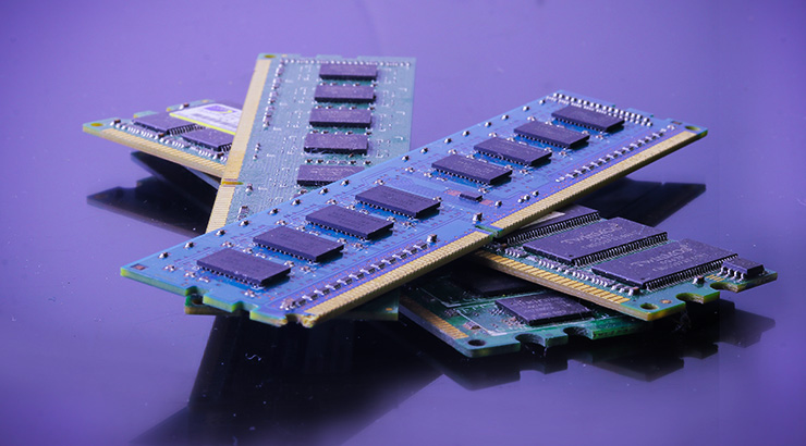 Na fioletowym tle leżą układy pamięci RAM z czarnymi chipami i złotymi złączami krawędziowymi.