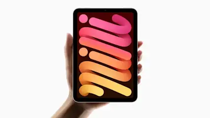 Dłoń trzyma tablet z abstrakcyjnym, kolorowym wzorem na ekranie, na białym tle.