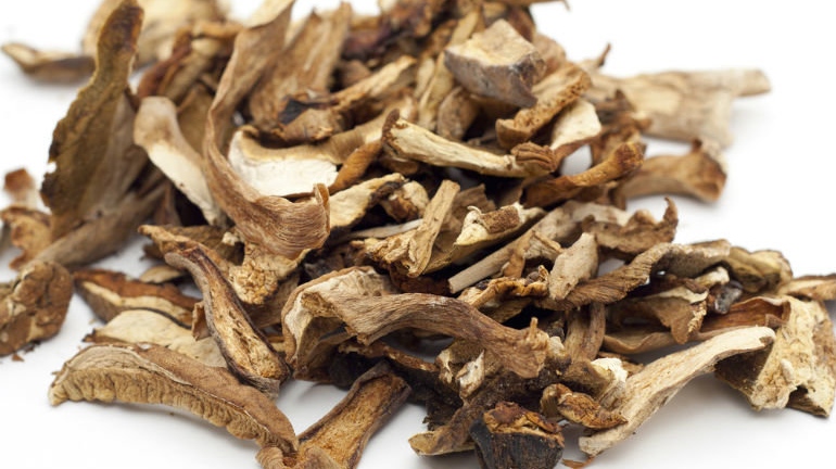 Garść suszonych grzybów na białym tle.