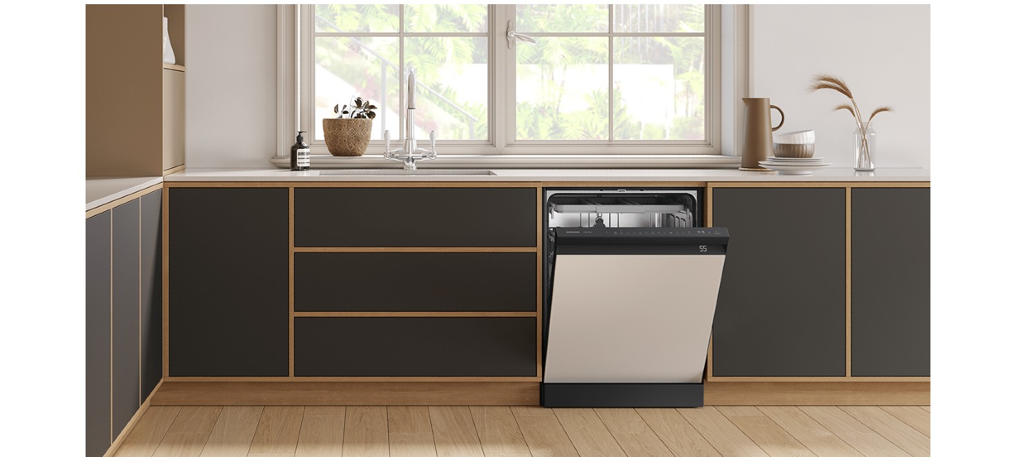 Kuchnia z drewnianą podłogą, ciemnymi szafkami i otwartą zmywarką. Nad blatem okno, zlew, roślina i naczynia.