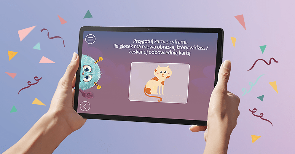 Dłonie trzymają tablet z aplikacją edukacyjną. Na ekranie jest kot, potwór i tekst o głoskach. Tło zdobią kolorowe kształty.