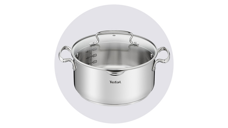 Srebrny garnek z uchwytami i miarką wewnątrz, przykryty szklaną pokrywką, na białym tle.