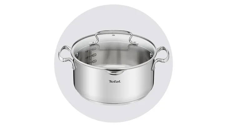 Srebrny garnek z uchwytami i miarką wewnątrz, przykryty szklaną pokrywką, na białym tle.