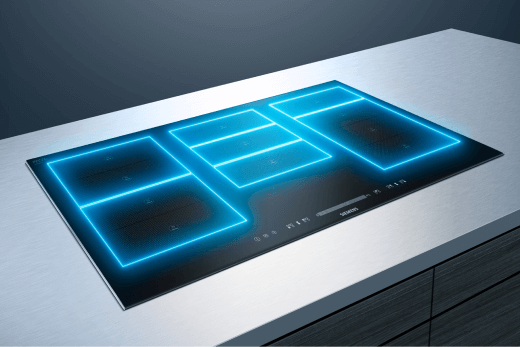 Czarna płyta indukcyjna na białym blacie, z niebieskimi obrysami pól grzewczych.