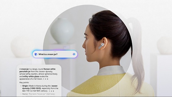 Osoba z kucykiem, twarz rozmyta, ma w uchu białą słuchawkę Buds4 pro; nad ramieniem widoczny pasek asystenta z pytaniem „What is a moon jar?” oraz po lewej karta z tekstową odpowiedzią; jasne, minimalistyczne tło.