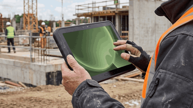 Mężczyzna trzymający tablet, będąc na budowie.