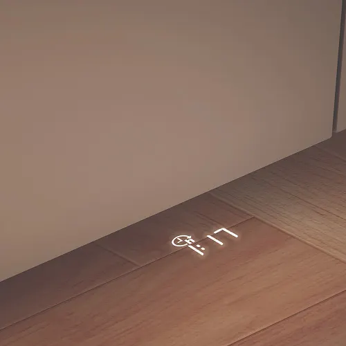 Na podłodze wyświetlony jest biały zegar cyfrowy. Podłoga jest brązowa, a ściana beżowa.