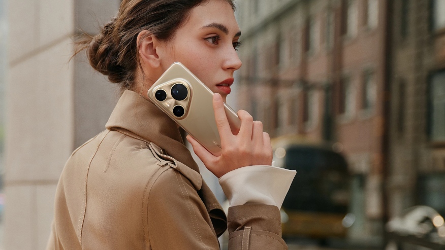 Kobieta w ciemnobeżowym płaszczu ze złotym telefonem Huawei Pura 80 Ultra przy uchu.