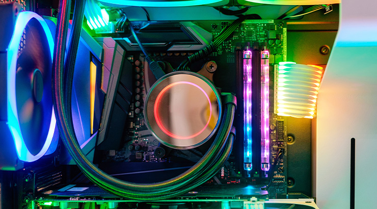 Wnętrze komputera z podświetleniem LED w kolorach: niebieskim, zielonym, różowym i pomarańczowym. Widoczne wentylatory i płyta główna.
