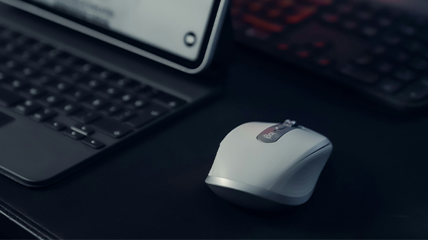 Biała mysz do pracy, profilowana, na ciemny biurku, obok laptopa.