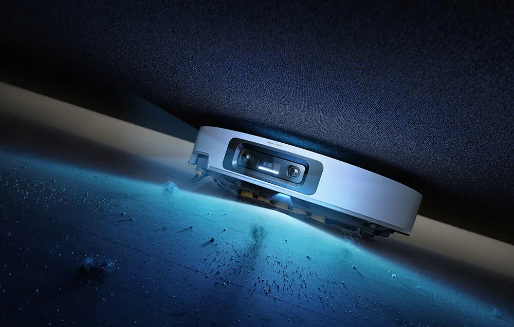 Na grafice znajduje się robot sprzątający, który w tym monecie odkurza pod łóżkiem, a jego światło podświetla bród, który sprząta robot.