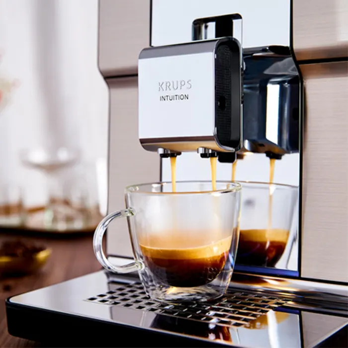 Ekspres Krups Intuition nalewa kawę do szklanki z podwójnymi ściankami. Kawa ma ciemny kolor i jest warstwowa.