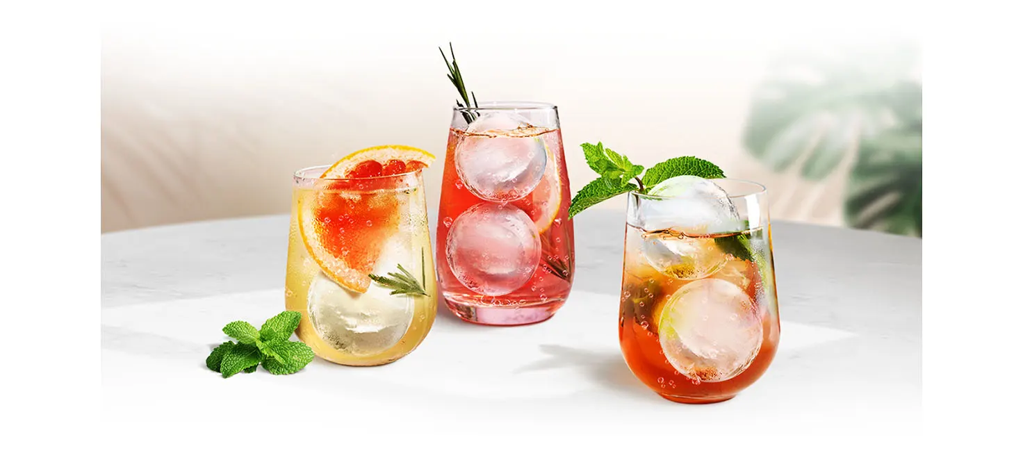 Trzy szklanki z wodą, lodem i selekcją owoców i mięty