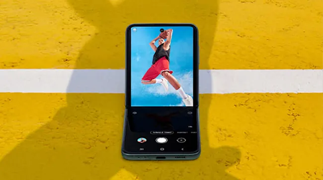 Na żółtym tle telefon z ekranem przedstawiającym osobę grającą w koszykówkę. Biała linia przecina tło.