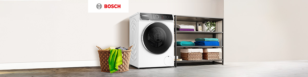 Widok na pralkę obok drewnianej szafki w kuchni, z szarymi szafkami z metalowymi uchwytami w tle.