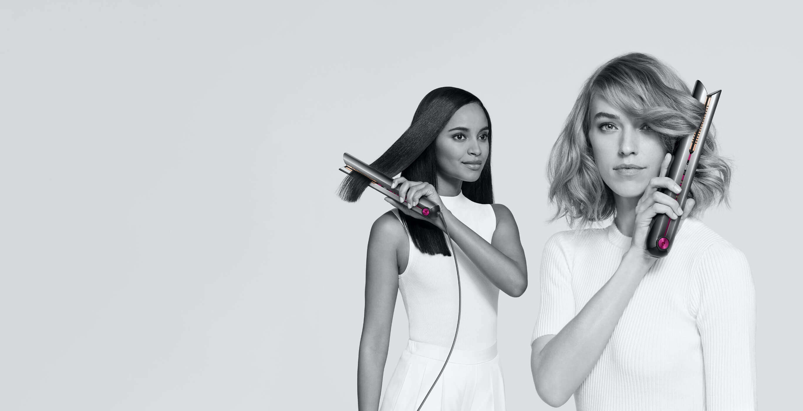 Dwie kobiety używają prostownicy do włosów na szarym tle.