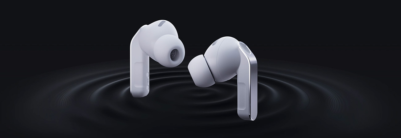 Dwie białe słuchawki dokanałowe buds4 pro unoszące się nad ciemnym tłem, skierowane ku sobie; silikonowe końcówki i srebrne wstawki na trzonkach, pod nimi koncentryczne fale dźwięku.