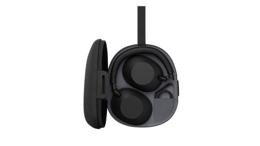 Czarne słuchawki w etui. Etui jest otwarte, a obok leży jego pokrywa. W tle białe tło.