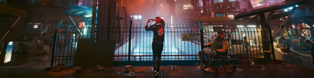 Na pierwszym planie metalowe ogrodzenie, za nim postać w czarnym ubraniu tworzy dłońmi kształt serca. Po prawej osoba na wózku.