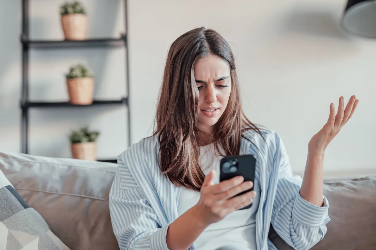 Femme regardant son smartphone avec confusion et réfléchissant à la manière de supprimer son compte Instagram.