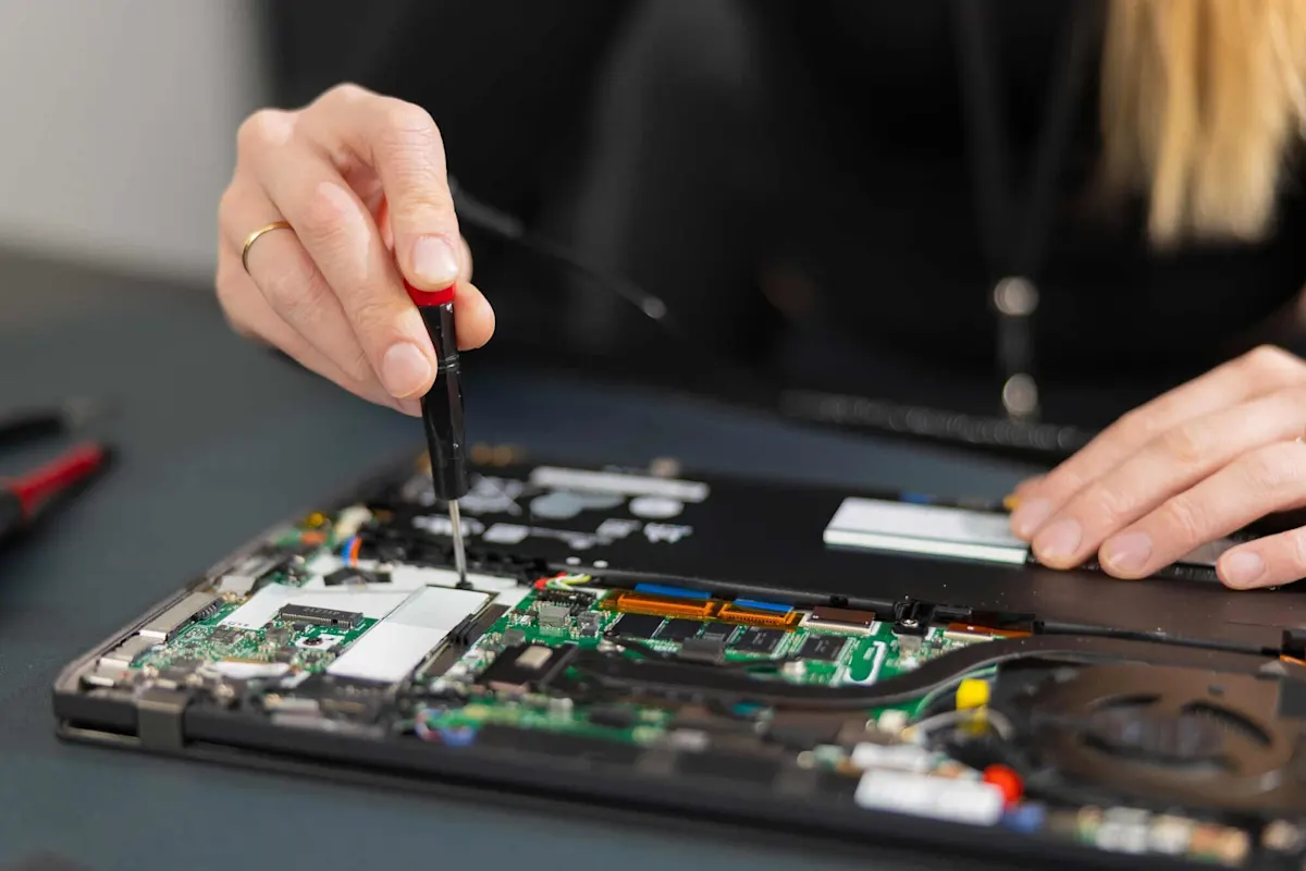 Person öffnet einen Computer, Blick auf das Innengehäuse mit RAM- und SSD-Modulen sichtbar. 