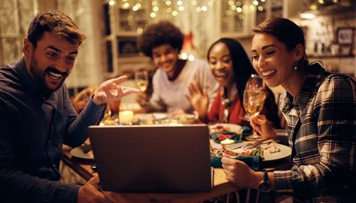 4 personnes souriantes sont assises à une table et regardent un ordinateur portable.