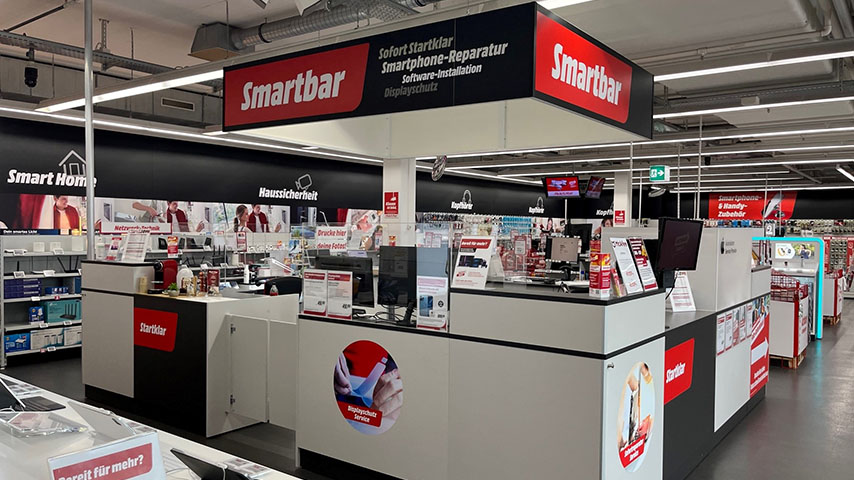 Ein Smartbar-Stand mit schwarzer Beschriftung in einem Geschäft, der Smartphone-Reparaturdienste und Zubehör anbietet.