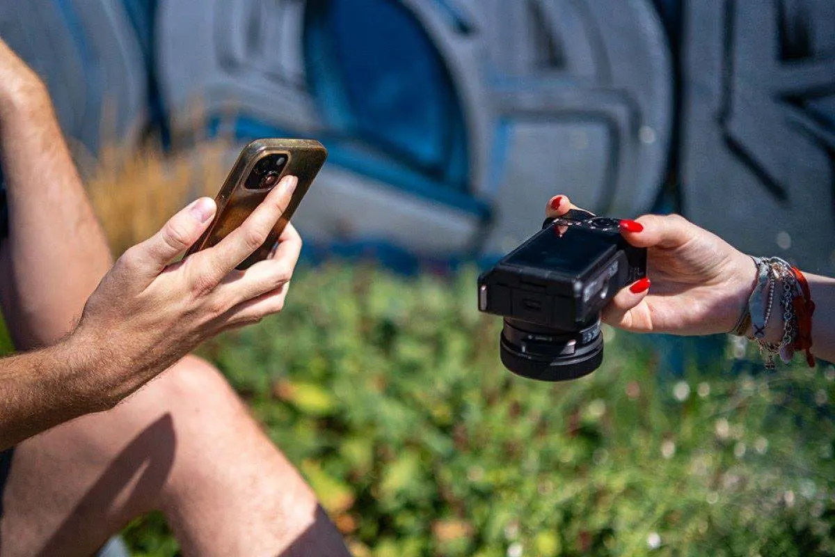 Una persona tiene uno smartphone, la seconda una fotocamera. 