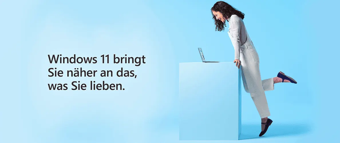 Eine Frau beugt sich über einen Laptop, der auf einem blauen Quader steht, vor blauem Hintergrund mit Text: Windows 11 bringt Sie näher an das, was Sie lieben.