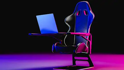Ein blauer Laptop steht auf einem Tisch, der an einem schwarzen Gaming-Stuhl mit blauen Akzenten befestigt ist, vor einem schwarzen Hintergrund.