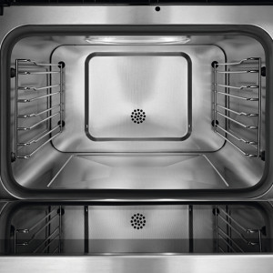 Intérieur d'un four vide en métal, avec des grilles latérales et des évents circulaires au fond et au centre.