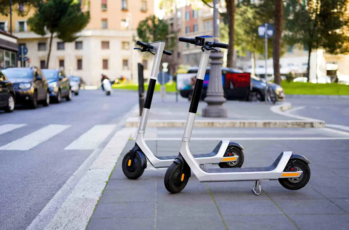Due e-scooter parcheggiati uno accanto all’altro vicino a un passaggio pedonale. 