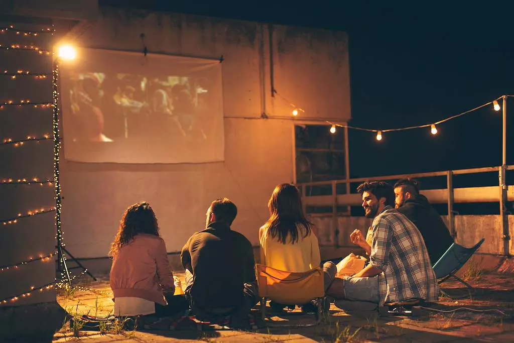 Watchparty en plein air : un groupe d’amis regarde quelque chose ensemble sur un grand écran.