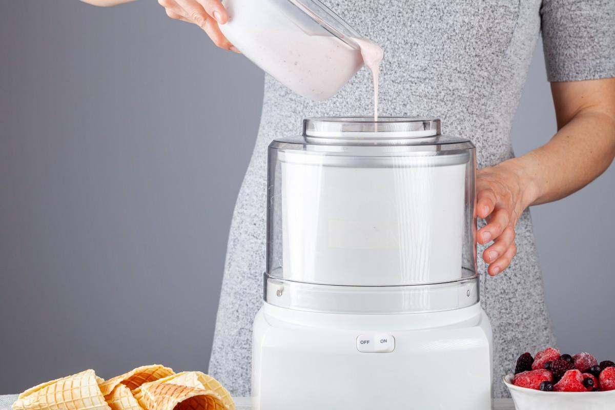 Una donna versa il composto liquido di gelato in una macchina per gelato. 