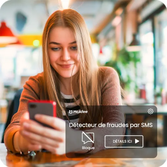 Une femme tient un smartphone avec une notification McAfee "Détecteur de fraudes par SMS". L'arrière-plan est un café.