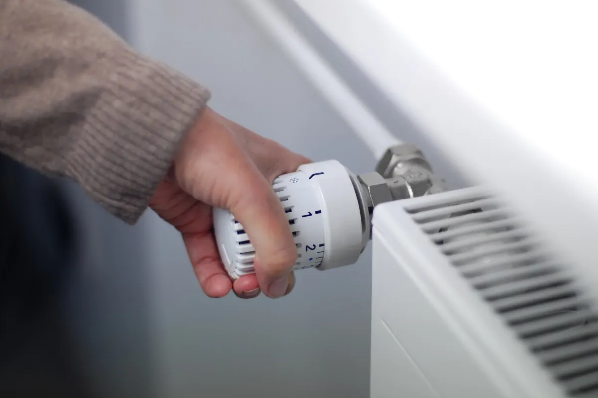 Una persona apre una finestra per arieggiare e rinnovare l’aria in casa.