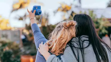 Zwei Frauen machen gemeinsam ein Selfie mit einer Sofortbildkamera.