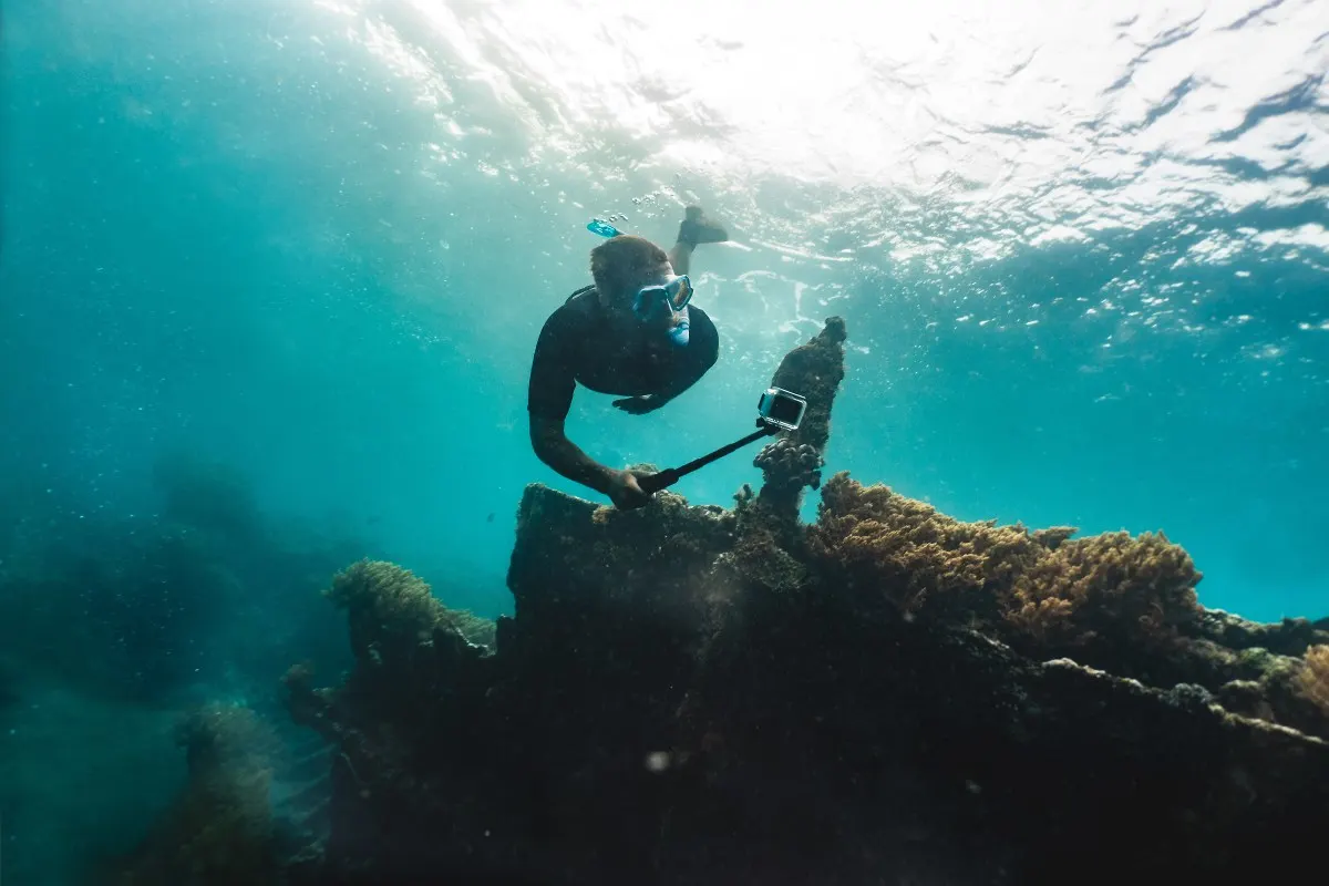 Plongeur filmant sous l’eau avec une caméra d’action fixée à un support.