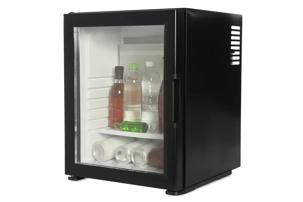 Mini-réfrigérateur noir avec porte vitrée, contenant diverses bouteilles et canettes.